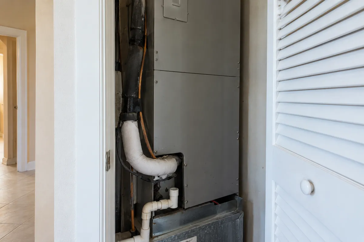 Indoor air handler cabinet with refrigerant lines and a white condensate drain, ac repair in Las Vegas, NV