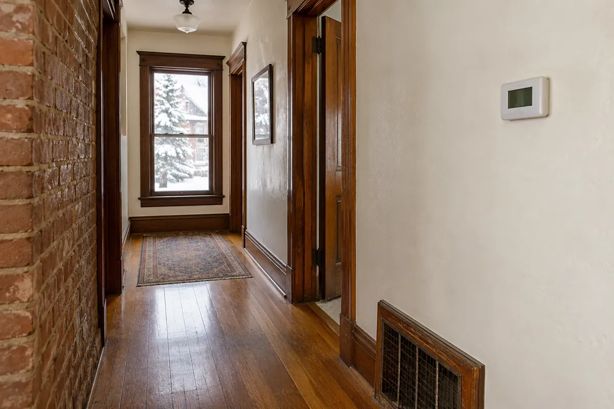 Hallway thermostat beside a brick wall and a floor register, thermostat installation in Las Vegas, NV